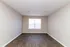 Spacious room with elegant wood flooring, neutral walls, and a bright window, ideal for a cozy living space.