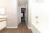 Bright bathroom with modern fixtures, elegant wood flooring, and a spacious tub, leading to a cozy bedroom through an inviting hallway.