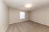 Bright and inviting bedroom with soft carpet flooring, neutral walls, and ample natural light from a large window.
