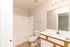 Modern and bright bathroom featuring a large mirror, elegant lighting, and pristine tile flooring.