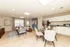 Bright and modern open-concept living room and kitchen with stylish decor, featuring a cozy seating area, elegant dining table, and sleek stainless steel appliances.