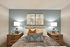 Elegant bedroom with a cozy bed, plush pillows, and soft lighting, featuring modern art and wooden side tables for a warm, inviting atmosphere.