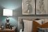 Elegant bedroom corner with soft lighting, stylish abstract art, and plush pillows creating a cozy atmosphere.