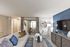 Chic living room featuring a plush sofa with vibrant cushions, elegant decor, and a modern entertainment center against a stylish blue accent wall.