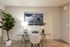 Inviting workspace featuring a chic glass desk, modern art, and vibrant indoor plant for a refreshing home office vibe.