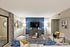 Inviting modern living room with elegant decor, featuring a sleek blue accent wall, cozy seating, stylish lamps, and a contemporary coffee table arrangement.