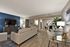 Contemporary living room with elegant blue accent wall, cozy seating area, and stylish open dining space. Features sleek modern furniture and abundant natural light.