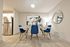 Elegant dining area with modern table, vibrant blue chairs, and sleek stainless steel fridge in the background, perfect for stylish entertaining.
