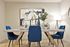 Elegant dining area featuring a modern table with vibrant blue chairs and abstract wall art, complemented by stylish decor and mood lighting.