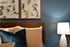 Elegant bedroom with sophisticated bird artwork, plush pillows, and ambient lighting for a cozy atmosphere.