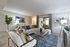Modern living room with elegant decor, featuring a plush gray sofa and stylish accent chairs. Bright, open space with contemporary art, sleek coffee table, and abundant natural light.