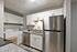 Modern kitchen with stainless steel appliances, sleek white cabinets, and in-unit washer and dryer for convenient living.
