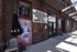 Charming entrance to a music venue with vibrant concert posters, set against a rustic brick facade, showcasing upcoming performances at Songbirds Guitar and Pop Culture Museum.
