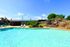 Inviting outdoor pool area with sparkling blue water, surrounded by comfortable lounge chairs and lush greenery, perfect for relaxation and leisure.