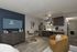 Modern studio apartment with a stylish kitchenette, cozy seating area, and a sleek wall-mounted TV. Elegant wood flooring complements the chic decor.