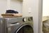 Modern laundry room featuring a sleek LG ThinQ washer, complemented by neatly folded towels on top.