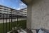 Charming apartment balcony with cozy seating overlooking a modern courtyard and clear blue skies.