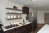 Modern kitchen with sleek dark wood cabinets, elegant open shelving, and stainless steel appliances, offering a chic and functional space.