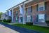 Charming brick apartment building with elegant pillars and vibrant green landscaping under a clear blue sky.
