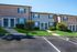 Charming two-story apartment building with classic brick facade, lush green landscaping, and convenient front entrances, perfect for comfortable living.
