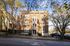 Charming brick apartment building with classic architecture, surrounded by mature trees on a sunny street.