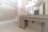 Modern bathroom with elegant granite countertop, spacious vanity, and a sleek bathtub with tiled walls.