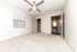 Bright, inviting bedroom featuring plush carpeting, modern ceiling fan, and ample natural light with access to an elegant ensuite bathroom.