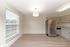 Bright and modern kitchen with stainless steel appliances, hardwood floors, and natural light pouring through large windows.
