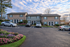 Charming apartment building with brick facade, surrounded by vibrant flower beds and ample parking under a picturesque sky.