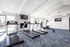 Bright modern gym with quality treadmills and exercise bike, featuring a stylish fireplace and large windows providing natural light.