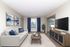 Inviting living room with elegant decor, featuring a comfy beige sofa, modern wooden coffee table, and stylish blue accents.