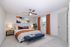 Elegant bedroom with a plush bed, vibrant artwork, and a sophisticated color palette of orange and blue accents.