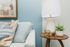 Chic living space with modern decor featuring an elegant wood side table, stylish lamp, abstract art, and cozy cushions in a cool-toned setting.