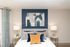 Cozy bedroom with stylish geometric artwork, plush pillows, and elegant bedside lamps, creating a serene retreat.