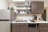 Contemporary kitchen with sleek modern cabinets, a stainless steel refrigerator, and stylish open shelving, offering functionality and elegance.