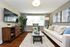 Chic and modern living room with a cozy beige sofa, vibrant green plant, and large windows offering abundant natural light.