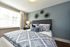 Bright and inviting bedroom with elegant decor, featuring a plush bed with blue patterned bedding, modern wall art, and abundant natural light through large windows.