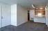 Inviting open-plan living area with plush carpeting, modern kitchen, and elegant lighting, perfect for stylish urban living.