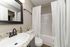 Modern bathroom with elegant granite countertop, sleek sink, and polished fixtures, complemented by a chic shower curtain and subtle floral decor.