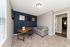 Bright home office with a cozy gray sofa, sleek wooden desk, and modern wall art, perfect for productivity and relaxation.