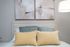 Chic bedroom setup with elegant abstract paintings, plush pillows in soothing hues, and a stylishly textured wooden headboard.