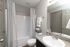 Modern bathroom featuring a sleek sink with a granite countertop, elegant fixtures, and a pristine bathtub with soft gray shower curtains.