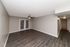 Spacious living room featuring sleek hardwood floors, modern ceiling fan, and elegant French doors leading to a cozy hallway.