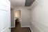 Spacious walk-in closet with sleek white shelving and a view into a modern bathroom featuring elegant fixtures and wood-style flooring.