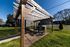 Charming outdoor space featuring a wooden pergola, green picnic tables, and a modern grill for community gatherings.