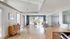 Bright and inviting office space with modern decor, featuring elegant wood flooring, stylish furniture, and natural light from large windows.