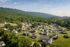 Charming aerial view of a picturesque neighborhood nestled among lush green hills, showcasing cozy homes and tranquil surroundings.