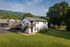 Charming two-story apartment building nestled in a lush green landscape with scenic mountain views, ample parking, and serene surroundings.