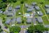Aerial view of a charming apartment complex with lush green lawns, a central swimming pool, and convenient walking paths.