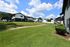 Charming apartment complex with well-manicured lawns, surrounded by scenic greenery and bright blue skies.